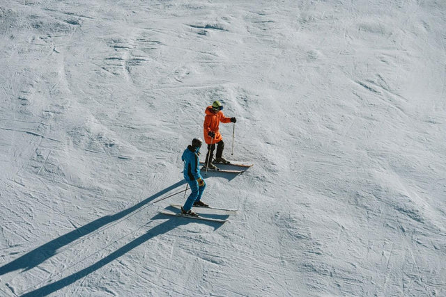 Monitor de esquí explicando la técnica a un alumno en una pista de Baqueira